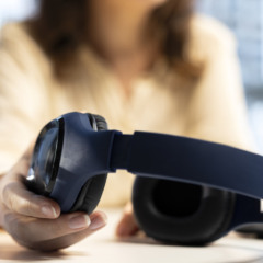 Young businesswoman reaching for her headphones for multitasking, working and listening to a podcast at the same time. Cheerful empowered director having fun with audio documentaries. Close up.