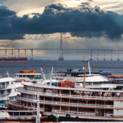 Foto de navios com a ponte Rio Negro ao fundo, em Manaus