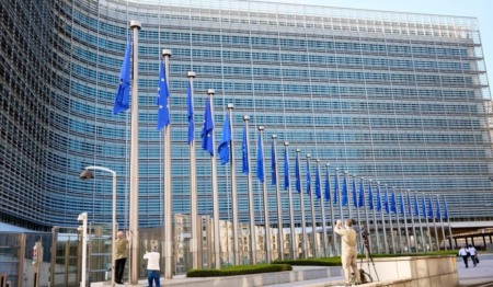 Edifício Berlaymont, sede da Comissão Europeia em Bruxelas, com uma fileira de mastros e bandeiras da União Europeia hasteadas Edifício Berlaymont, sede da Comissão Europeia em Bruxelas, com uma fileira de mastros e bandeiras da União Europeia hasteadas