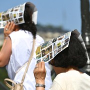Duas mulheres usando folhetos tur&iacute;sticos coloridos como prote&ccedil;&atilde;o improvisada contra o sol forte em um dia de ver&atilde;o europeu