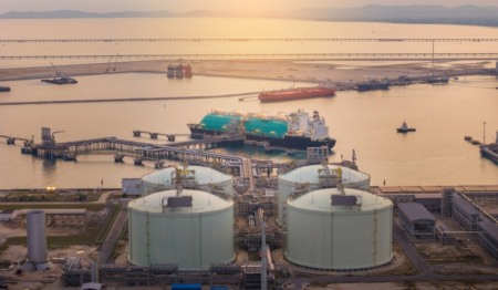 Terminal de gás natural, com quatro grandes tanques de armazenamento na costa e um navio cargueiro atracado no píer