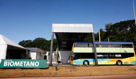 Posto de bimetano com placa e um ônibus com logo do governo federal, adaptado a andar com o combustível Posto de bimetano com placa e um ônibus com logo do governo federal, adaptado a andar com o combustível