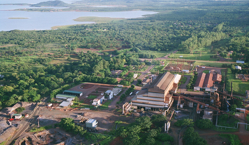 Foto de uma planta industrial rodeada por verde, com um rio ou lago ao fundo Foto de uma planta industrial rodeada por verde, com um rio ou lago ao fundo