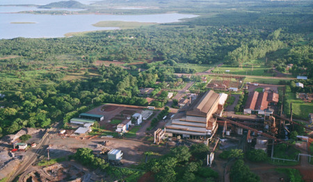 Foto de uma planta industrial rodeada por verde, com um rio ou lago ao fundo Foto de uma planta industrial rodeada por verde, com um rio ou lago ao fundo