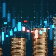 Pilhas de moedas de ouro em primeiro plano com um fundo de gr&aacute;fico financeiro digital