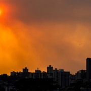 Horizonte de uma cidade com pr&eacute;dios. O c&eacute;u est&aacute; polu&iacute;do e laranja