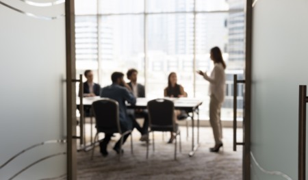 Silhouettes of businesspeople gathered in conference room for negotiation or seminar event, female leader standing inf front of audience makes speech or presentation, blurred view. Business meeting. Crédito: Shutterstock Silhouettes of businesspeople gathered in conference room for negotiation or seminar event, female leader standing inf front of audience makes speech or presentation, blurred view. Business meeting. Crédito: Shutterstock