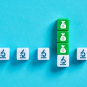 Cinco pe&ccedil;as com imagens de microsc&oacute;pios, simbolizando inova&ccedil;&atilde;o. Uma delas tem pe&ccedil;as verdes com a ilustra&ccedil;&atilde;o de dinheiro em cima