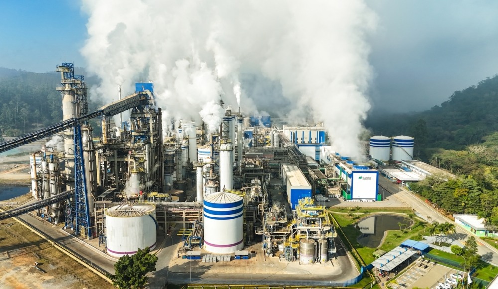 Vista aérea de uma grande instalação da indústria de papel e polpa com edifícios de fábrica, chaminés e equipamentos industriais sob céu claro Vista aérea de uma grande instalação da indústria de papel e polpa com edifícios de fábrica, chaminés e equipamentos industriais sob céu claro