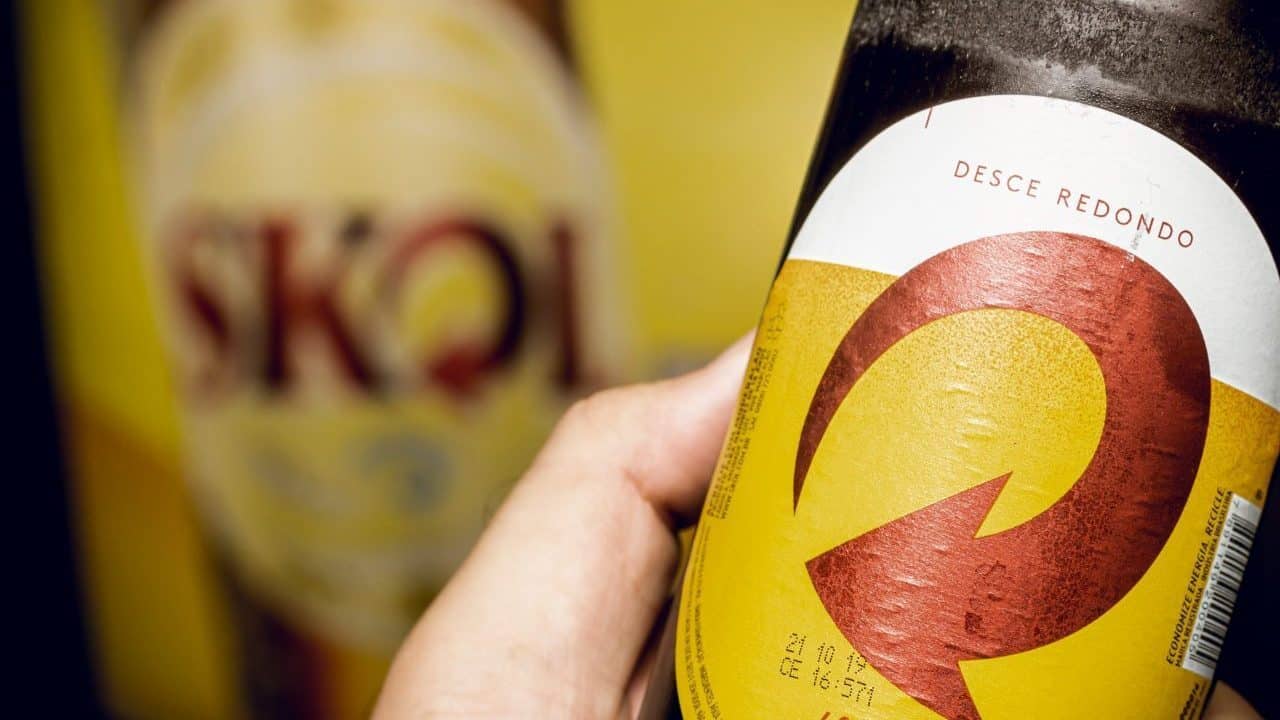 Mão segura cerveja Skoll, da Ambev, que quer zerar CO2