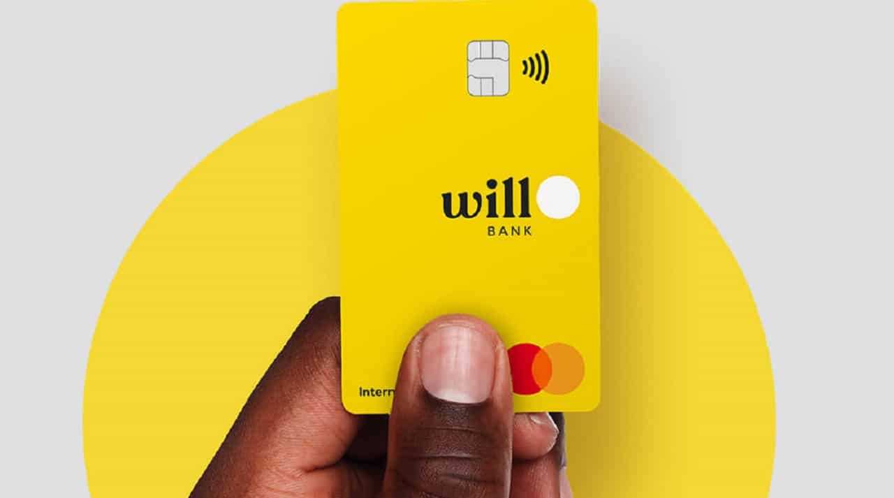 A mão de uma pessoa negra segura um cartão amarelo do Will Bank